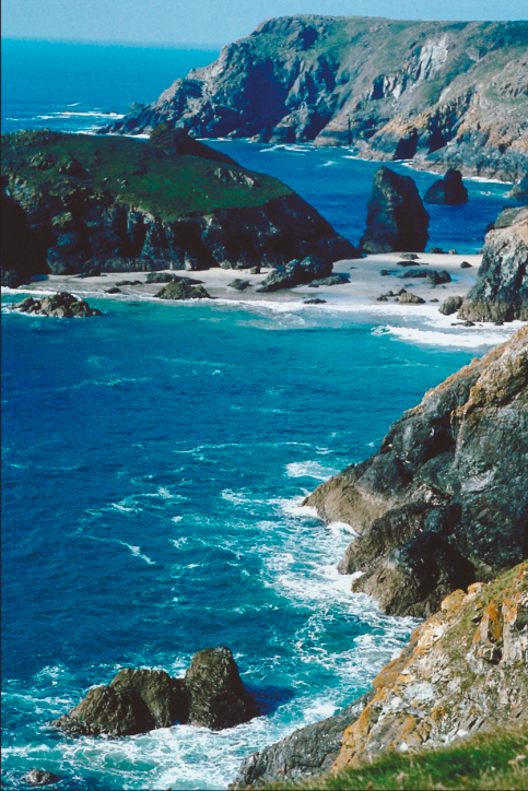 Von blauem Wasser umspülte raue Felsen an der Küste Cornwalls